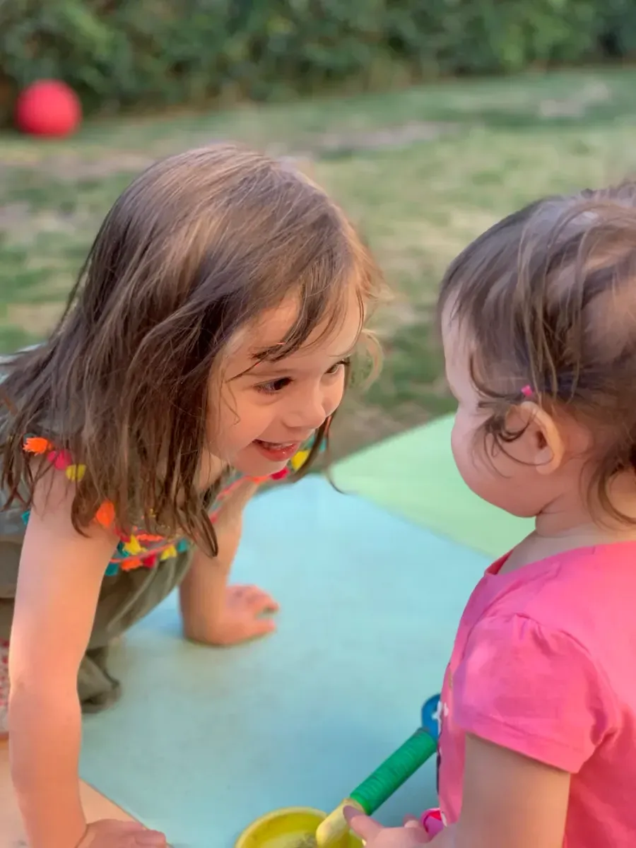 Two toddlers sharing a smile at a play table