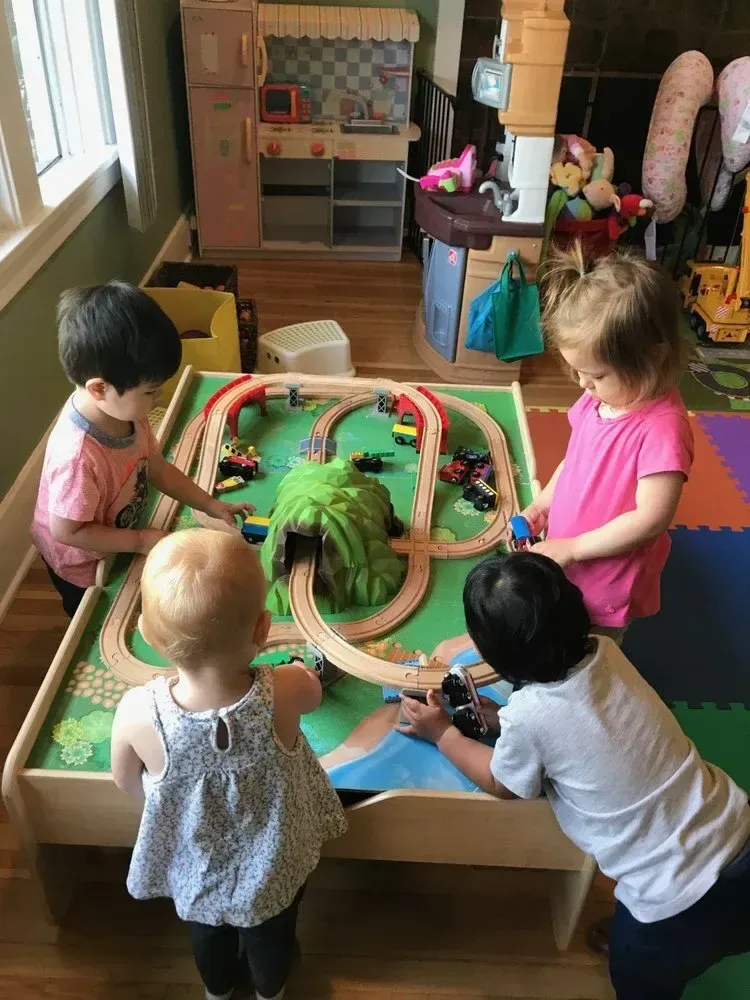 Toddlers playing together at a wooden train table